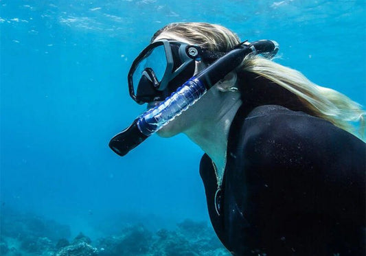 A woman with a snorkeling mask swims underwater